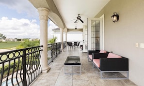 Eine überdachte Terrasse mit Sitzgelegenheit, Säulen und Blick auf einen Golfplatz.