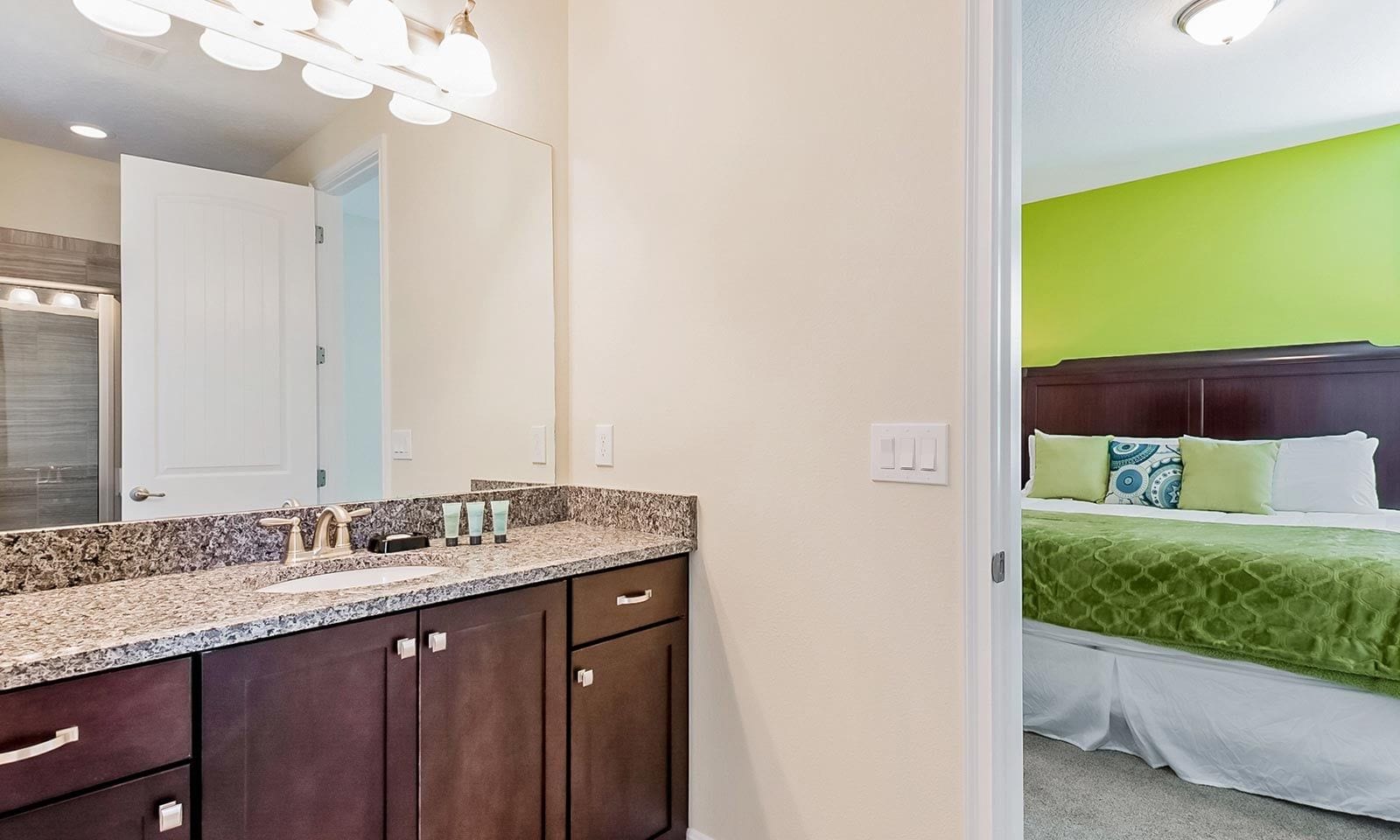 A bathroom with a granite countertop, dark wooden cabinets, and a large mirror.