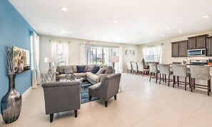 Ein großzügiger Wohnbereich mit einer Sofagarnitur, einem Esstisch mit Stühlen und einer Küchenzeile inklusive Mikrowelle.