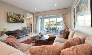 A modern living room with a sofa set, a coffee table, and a dining area with a table and chairs. - Sun-kissed Villa With Private Pool at Encore (Kissimmee)