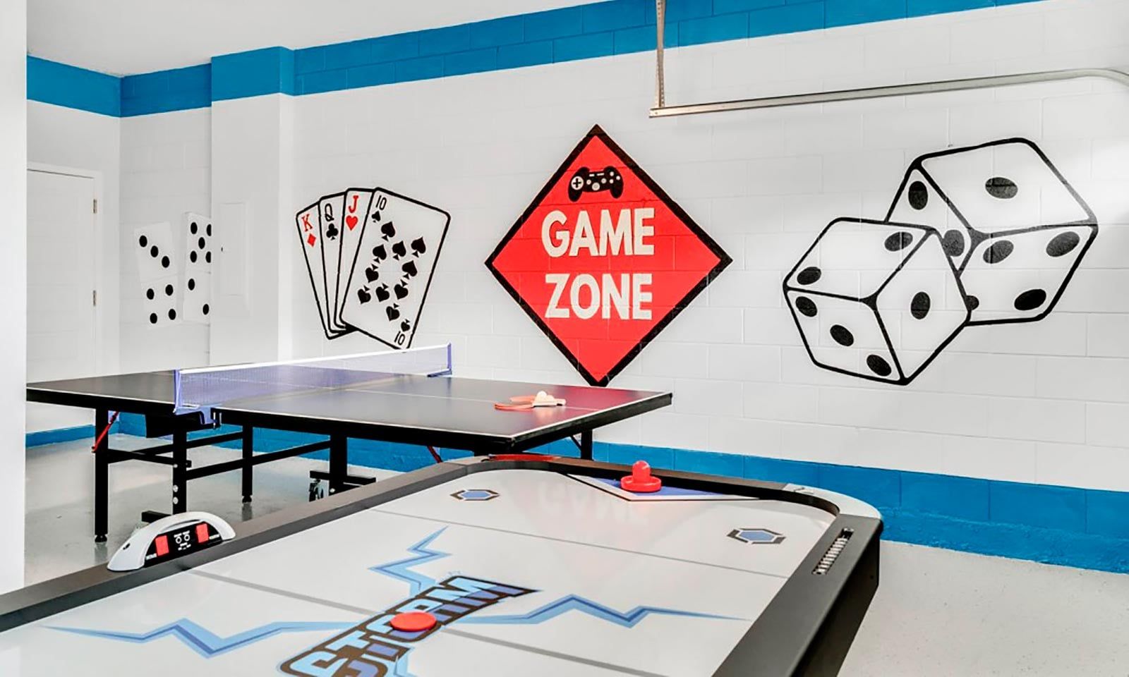 A room with a ping pong table, a foosball table, and a wall with a 'GAME ZONE' sign.