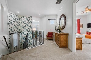 A hotel room with a staircase, a red chair, a wooden dresser, and a television. - Tropical Retreat With Screened in Private Pool and Spa at Reunion (Kissimmee)