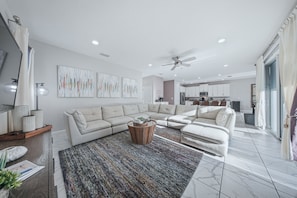 A modern living room with a sectional sofa, a coffee table, and artwork on the walls. - Orlando Luxury Home With Pool Heat Included (Kissimmee)