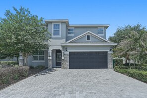 A two-story house with a garage, a front door, and a driveway. - Orlando Luxury Home With Pool Heat Included (Kissimmee)