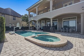A swimming pool with a hot tub, outdoor seating, and a covered patio area. - Upscale Oasis With Home Theater at Reunion (Kissimmee)