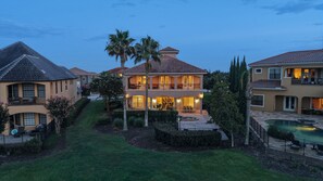 A two-story house with a balcony, a swimming pool, and a well-maintained lawn. - Upscale Oasis With Home Theater at Reunion (Kissimmee)