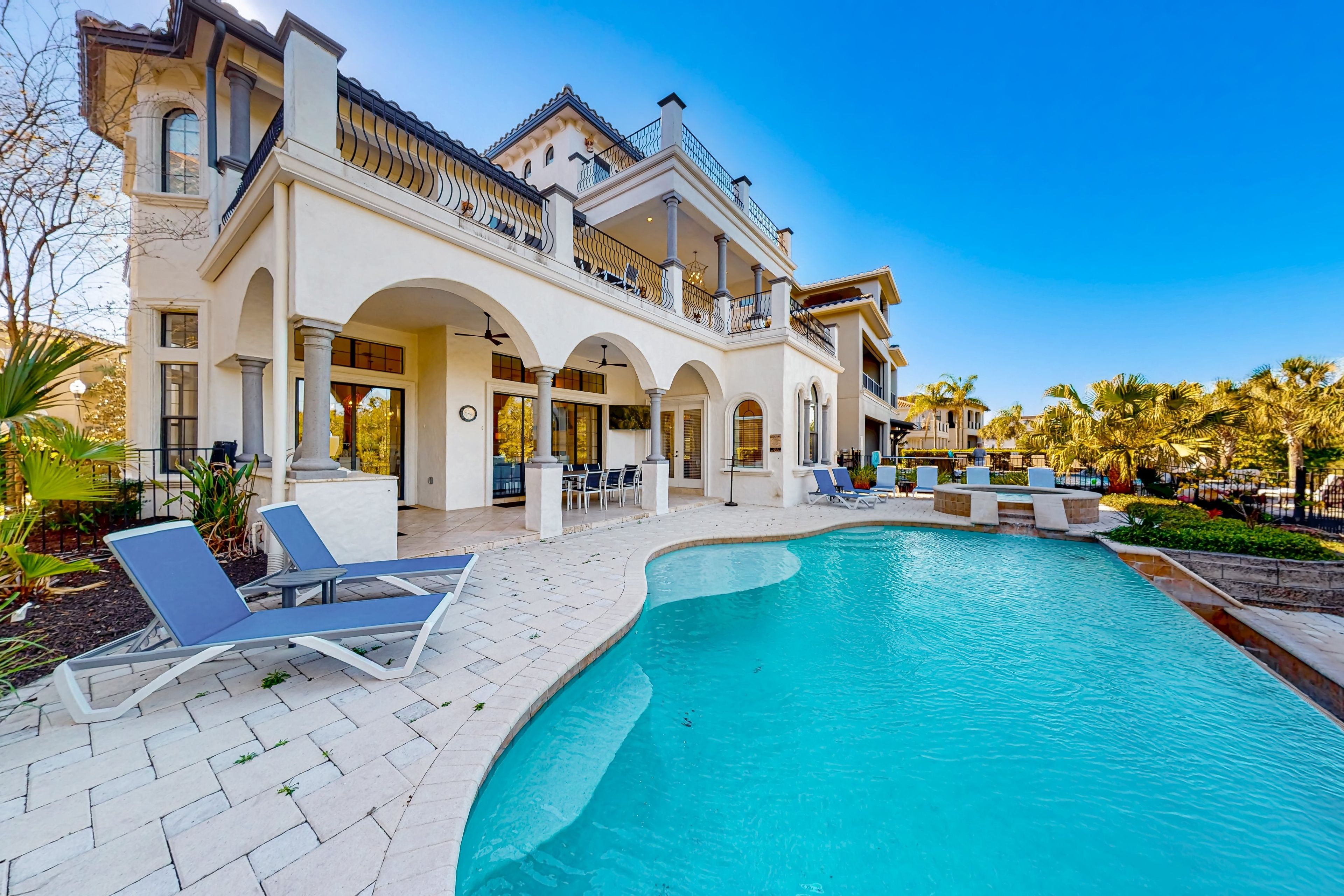 A large building with a swimming pool, outdoor seating, and a covered patio area.