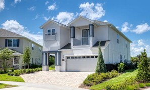 A modern two-story house with a garage, a covered entryway, and a well-maintained lawn. - Energetic Escape With Games Room at Encore (Kissimmee)