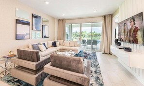 A modern living room with a beige sectional sofa, a coffee table, and a TV on a white console. - Energetic Escape With Games Room at Encore (Kissimmee)