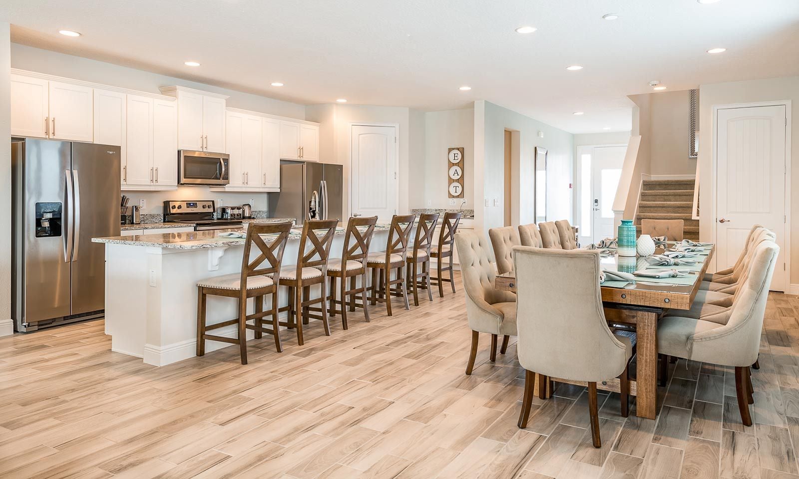 A modern kitchen with white cabinetry, stainless steel appliances, and a central island with bar stools.