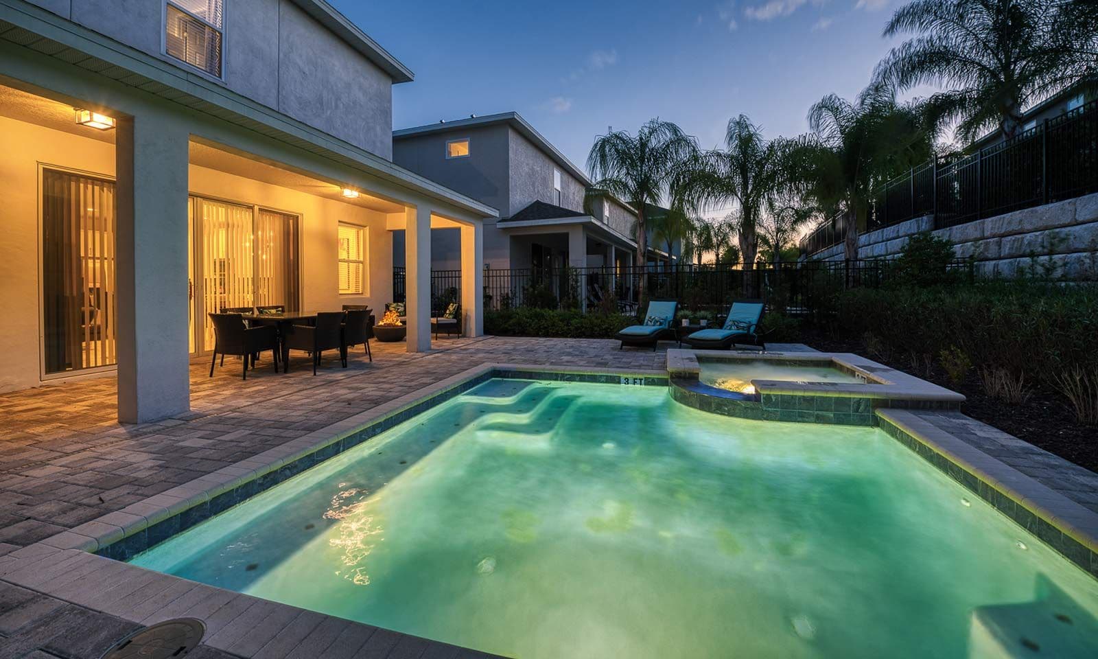 A swimming pool with a hot tub, outdoor seating, and a patio area.