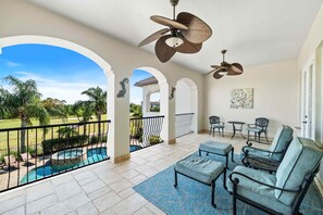 A spacious balcony with a pool, outdoor seating, and ceiling fans. - Noble Estate With Private Pool at Reunion (Kissimmee)