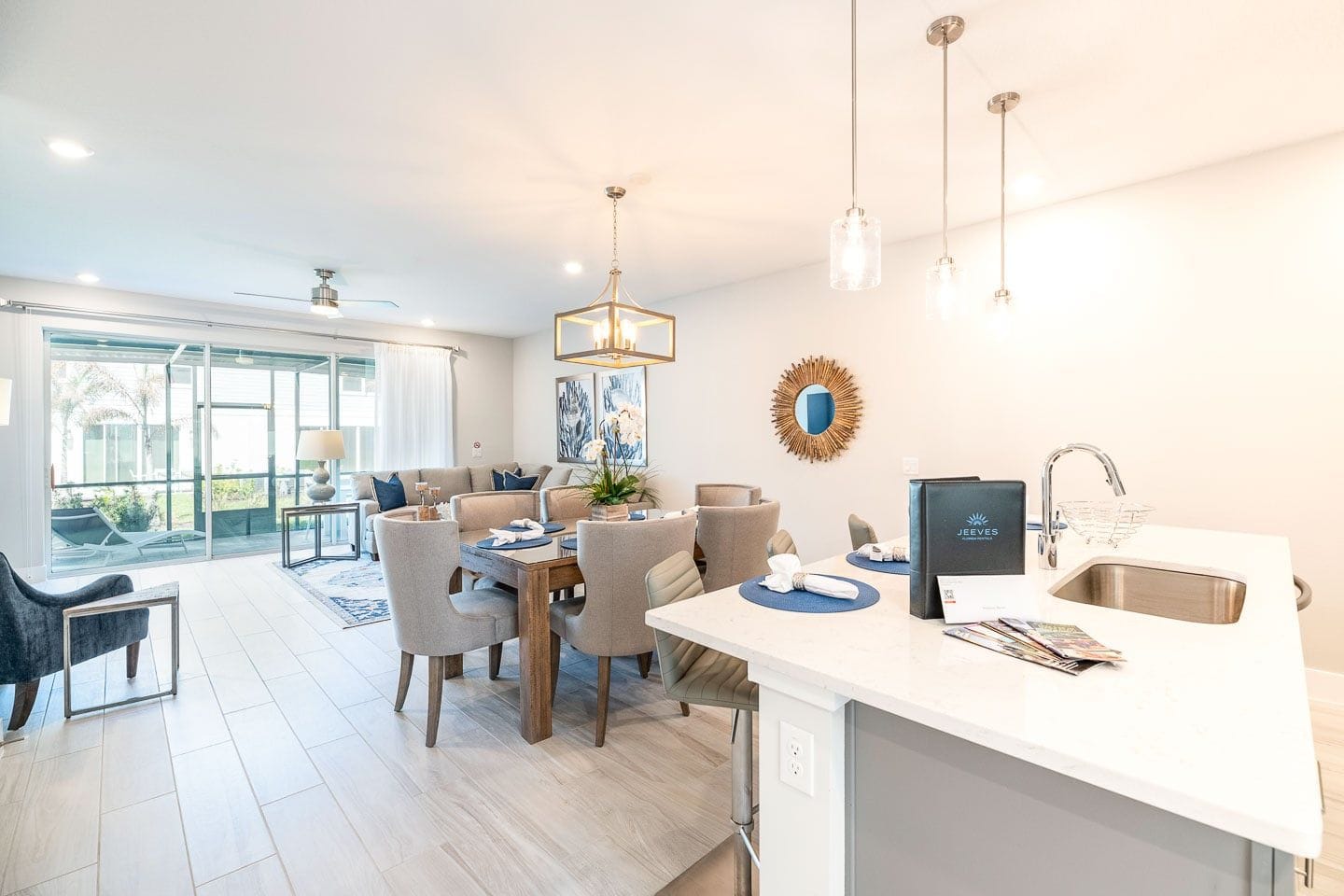 A modern kitchen with a dining area, large windows, and a view of the outdoors.