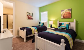 A bedroom with two beds, a nightstand, a lamp, and a bathroom visible in the background. - Sleek Residence With Theater Room at Reunion (Kissimmee)