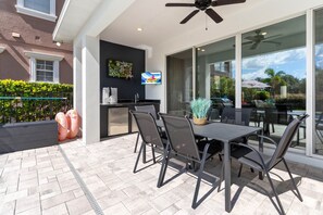 Eine Terrassenausstattung mit Tisch, Stühlen, Deckenventilator und Blick auf die Umgebung.