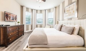 A bedroom with a large bed, a dresser, and a ceiling fan. - Large Spacious Villa With Private Pool and Water Slide at Encore (Kissimmee)