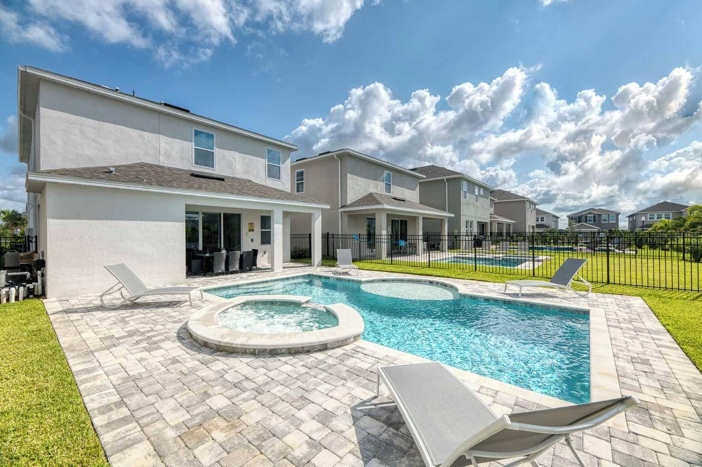 A residential area with a swimming pool, outdoor seating, and a covered patio.