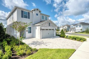 A two-story house with a stone facade, a garage, and a well-maintained lawn. - Encore Resort Villa With Pool & Spa (Kissimmee)