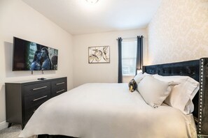 A bedroom with a bed, a dresser, a television, and artwork on the walls. - Encore Resort Villa With Pool & Spa (Kissimmee)