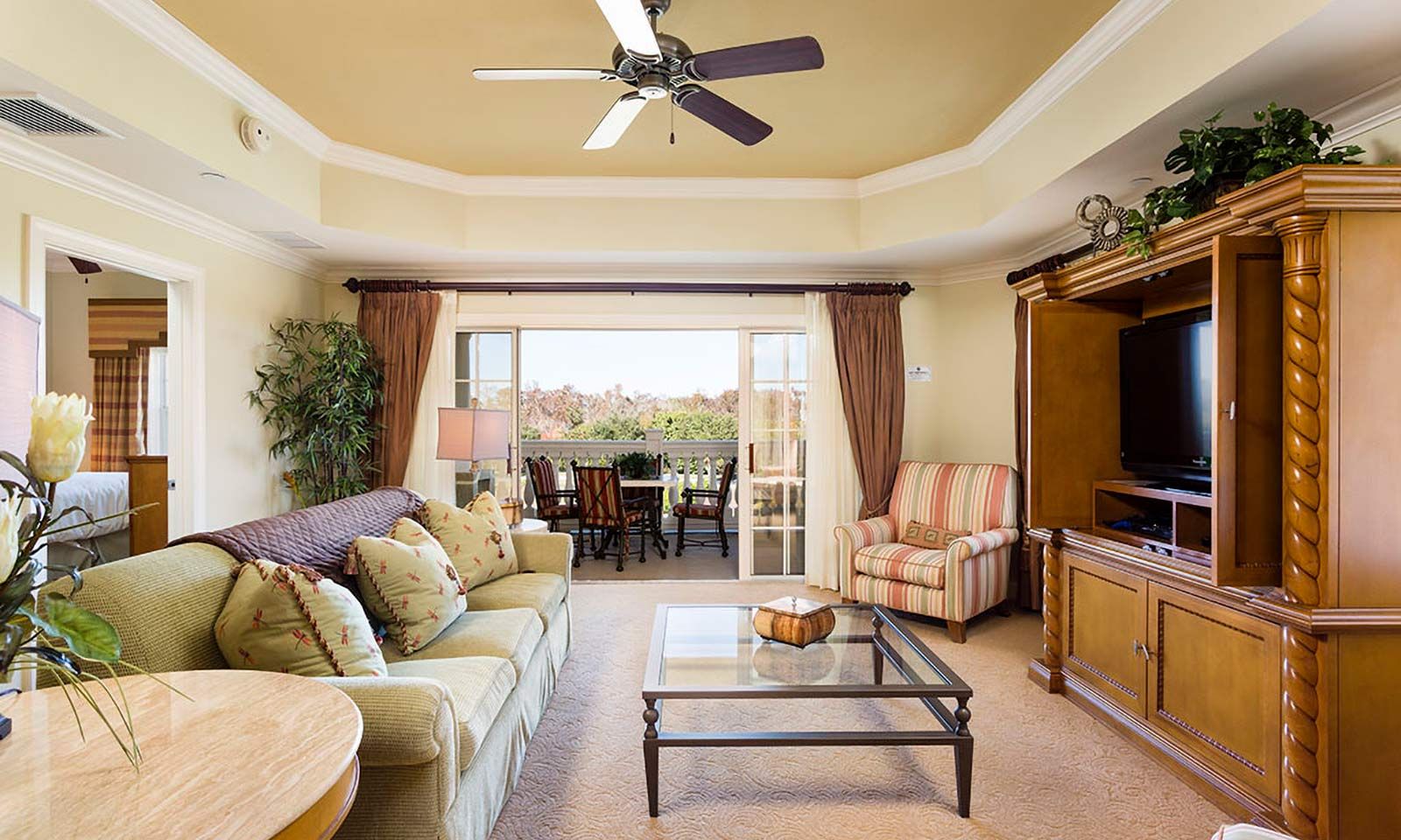 A spacious living room with a sofa, armchair, and a television on a wooden cabinet.