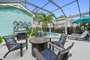 A covered outdoor area with a pool, lounge chairs, a grill, and a table. - Safari Explorer's Retreat w/ Theme Decor Private Pool (Kissimmee)