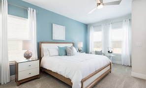 A bedroom with a bed, nightstands, a ceiling fan, and a window with curtains. - Modern 6 Bedroom Home With Upscale Living at Reunion (Kissimmee)