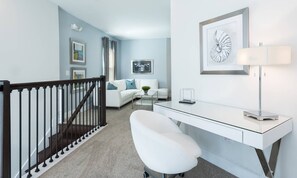 A modern living room with a white sofa, a glass coffee table, and a desk with a lamp. - Modern 6 Bedroom Home With Upscale Living at Reunion (Kissimmee)