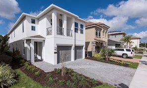 A modern two-story house with a garage, a balcony, and a driveway. - Modern 6 Bedroom Home With Upscale Living at Reunion (Kissimmee)