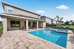 A modern house with a swimming pool, patio furniture, and a well-maintained lawn. - Stylish Sleek Home With Full Kitchen at Encore (Kissimmee)