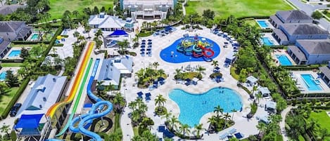An aerial view of a resort with a central pool, a water park, and multiple guest villas.