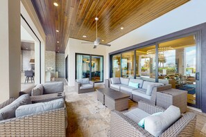 A spacious outdoor living area with wicker furniture, a ceiling fan, and large glass doors leading to a patio. - The Epic Portal Mansion (Kissimmee)