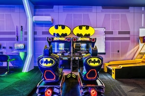 Two Batman arcade games in a room with purple lighting and a window with blinds. - Modern Villa With Games Room at Reunion (Kissimmee)