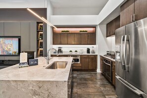 A modern kitchen with a large island, stainless steel appliances, and a flat-screen TV. - Modern Villa With Games Room at Reunion (Kissimmee)