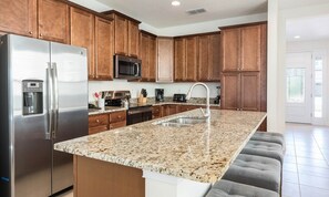 A modern kitchen with granite countertops, stainless steel appliances, and wooden cabinets. - Spacious Retreat With Themed Bedrooms in Encore (Kissimmee)