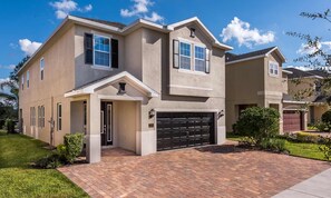 A two-story house with a garage, a front entrance, and a well-maintained lawn. - Spacious Retreat With Themed Bedrooms in Encore (Kissimmee)