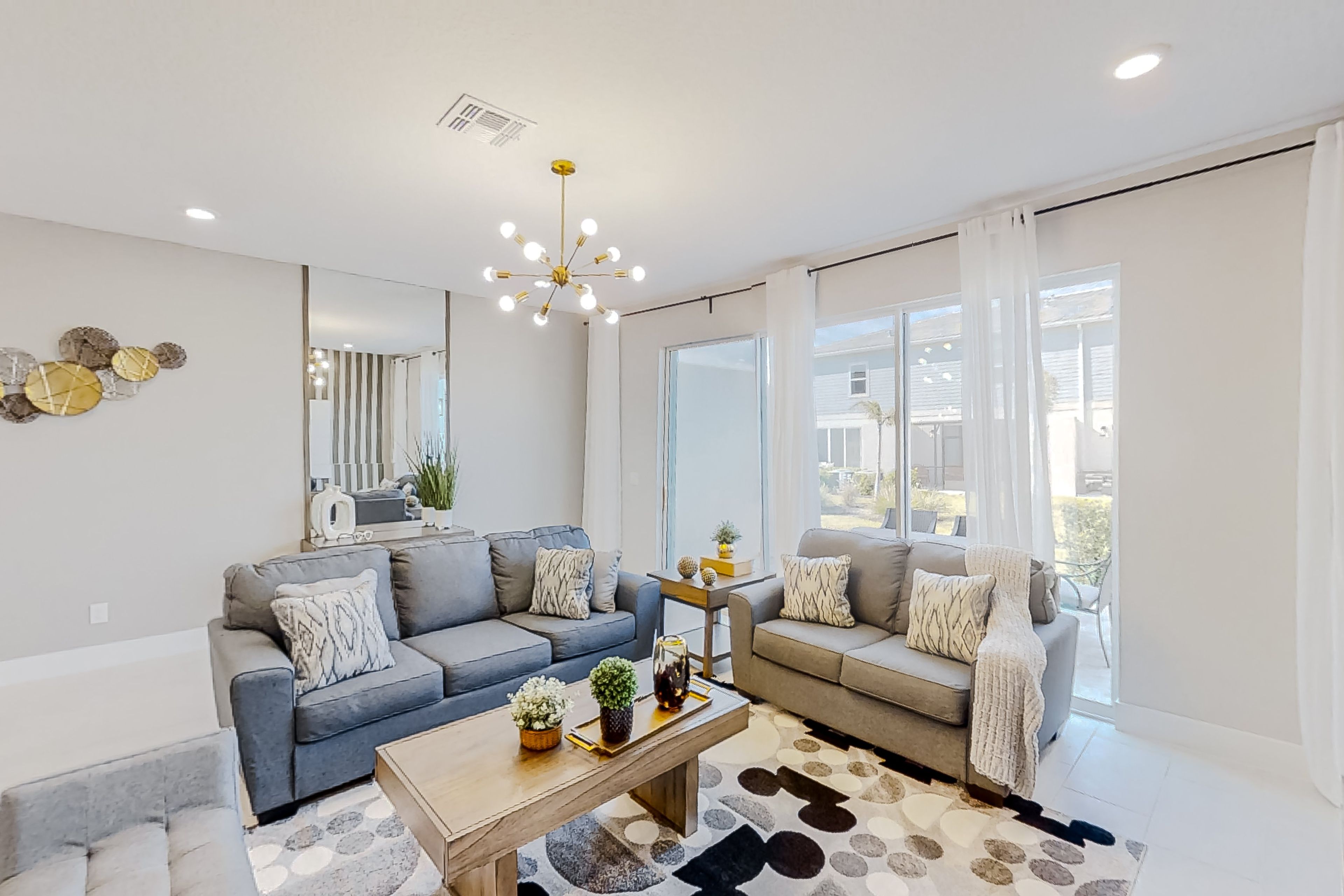 A modern living room with two sofas, a coffee table, and a chandelier.