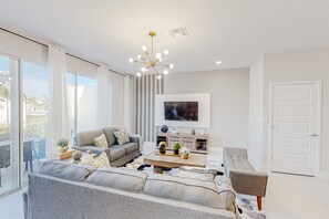 A modern living room with a sofa, coffee table, and TV. - Magical Sunny Townhouse With Games Room at Reunion (Kissimmee)