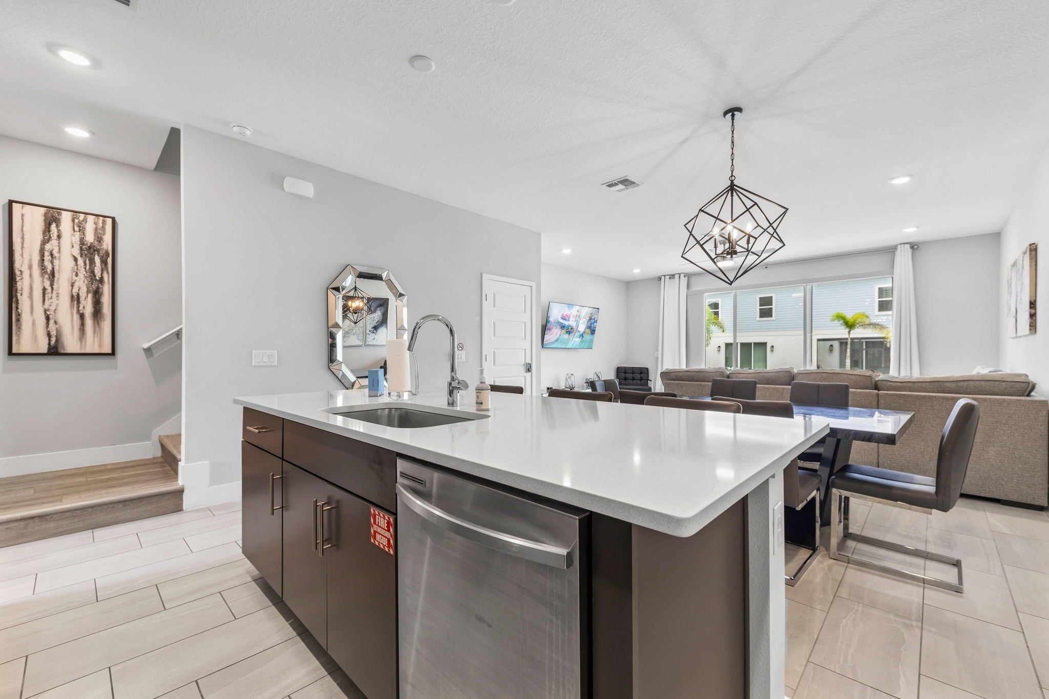 A modern kitchen with a central island, stainless steel appliances, and a dining area with a sofa and chairs.