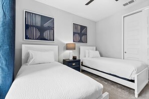 A hotel room with two beds, a nightstand, a lamp, and two abstract wall art pieces. - Getaway Townhome at Reunion Resort (Kissimmee)