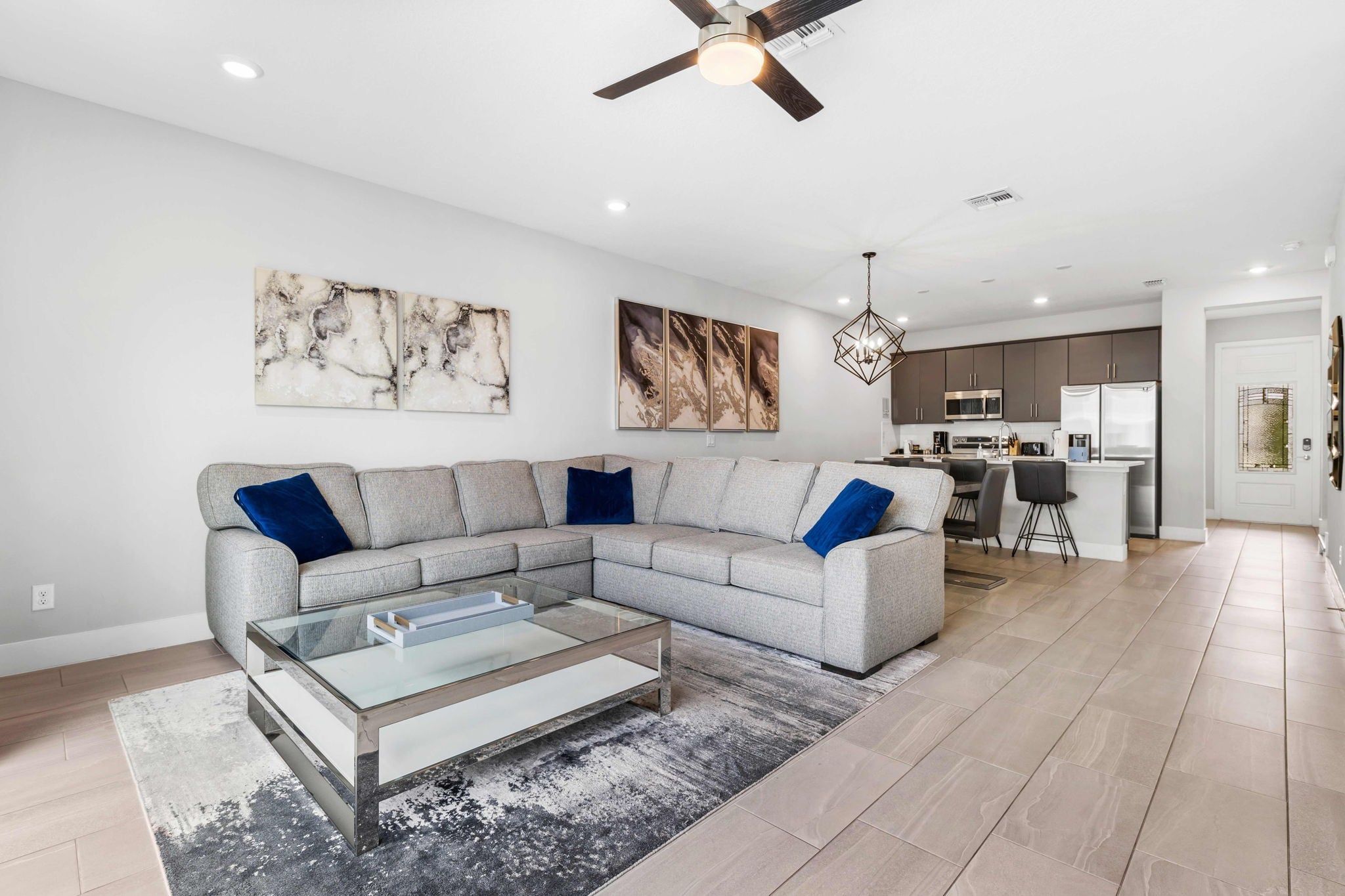 A modern living room with a sectional sofa, a glass coffee table, and artwork on the walls.