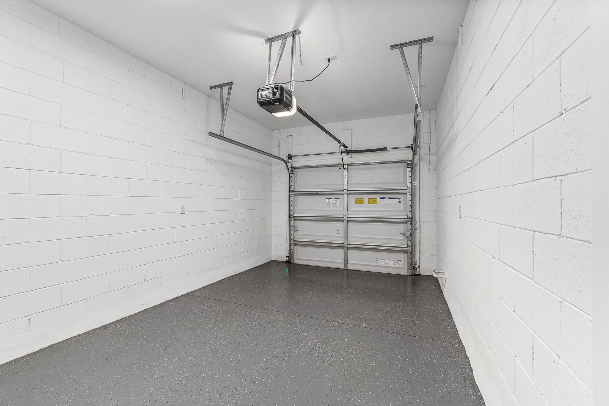 A clean, empty room with white brick walls, a grey floor, and a metal shelving unit against the wall.
