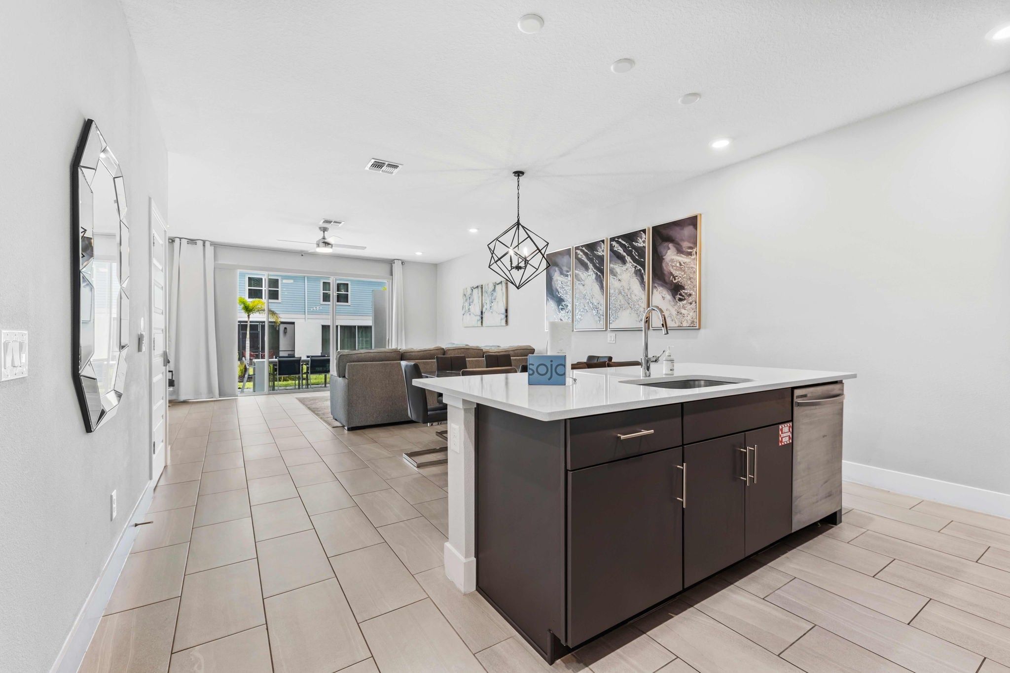 A modern kitchen with a central island, dark cabinetry, and a dining area with a sofa and chairs.