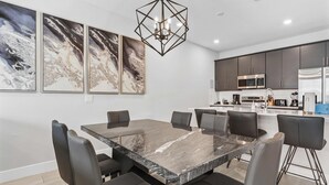 A modern kitchen with dark cabinets, a stainless steel refrigerator, and a built-in microwave. - Getaway Townhome at Reunion Resort (Kissimmee)