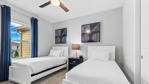 A bedroom with two single beds, a nightstand with a lamp, and a ceiling fan. - Getaway Townhome at Reunion Resort (Kissimmee)
