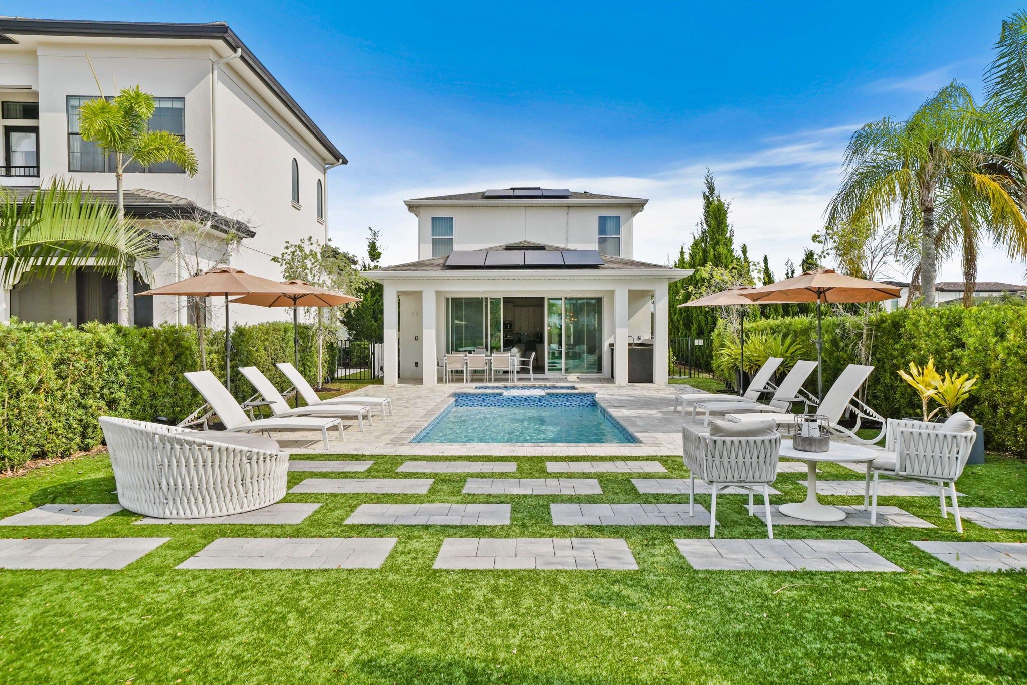 Una casa moderna con piscina, area salotto esterna e giardino curato.