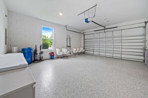 A clean, spacious garage with a concrete floor, a white wall, and a large garage door. - The Villa Tranquility With Private Pool (Kissimmee)