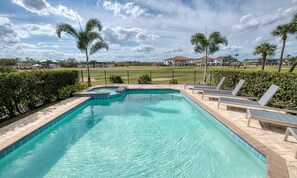 Ein rechteckiger Pool mit einer gefliesten Kante, umgeben von einem niedrigen Zaun und Palmen. Entlang des Poolbereichs befinden sich Liegestühle.