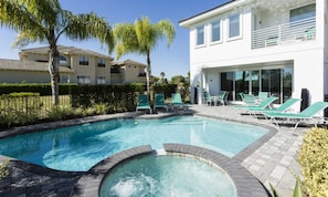 A swimming pool with lounge chairs and a modern building in the background. - Modern Villa With Fun Themed Bedrooms at Reunion (Kissimmee)