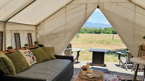 Uma tenda com sofá, mesa e vista para o exterior.