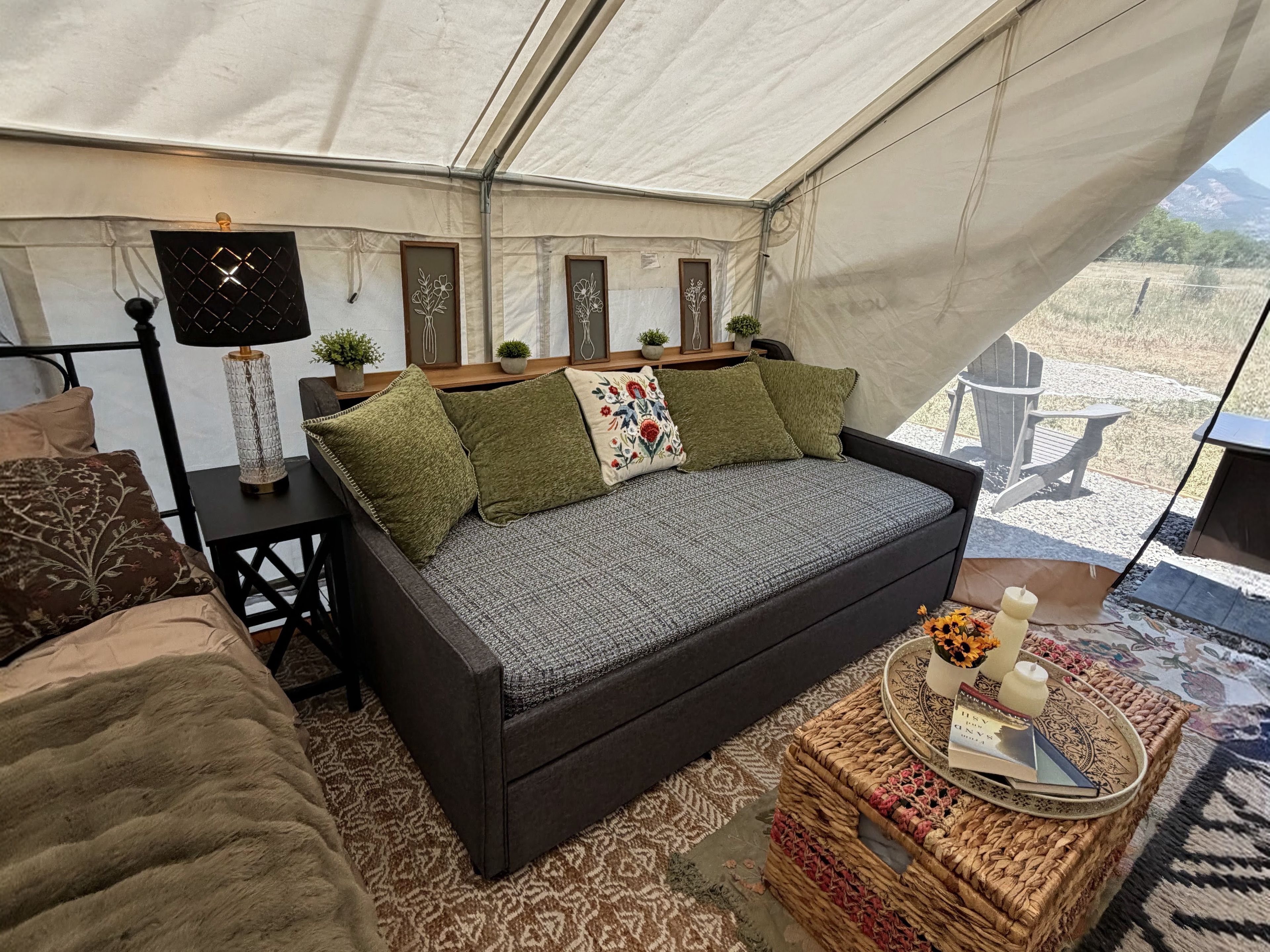 A tent interior with a sofa, a lamp, and a small table with decorative items.